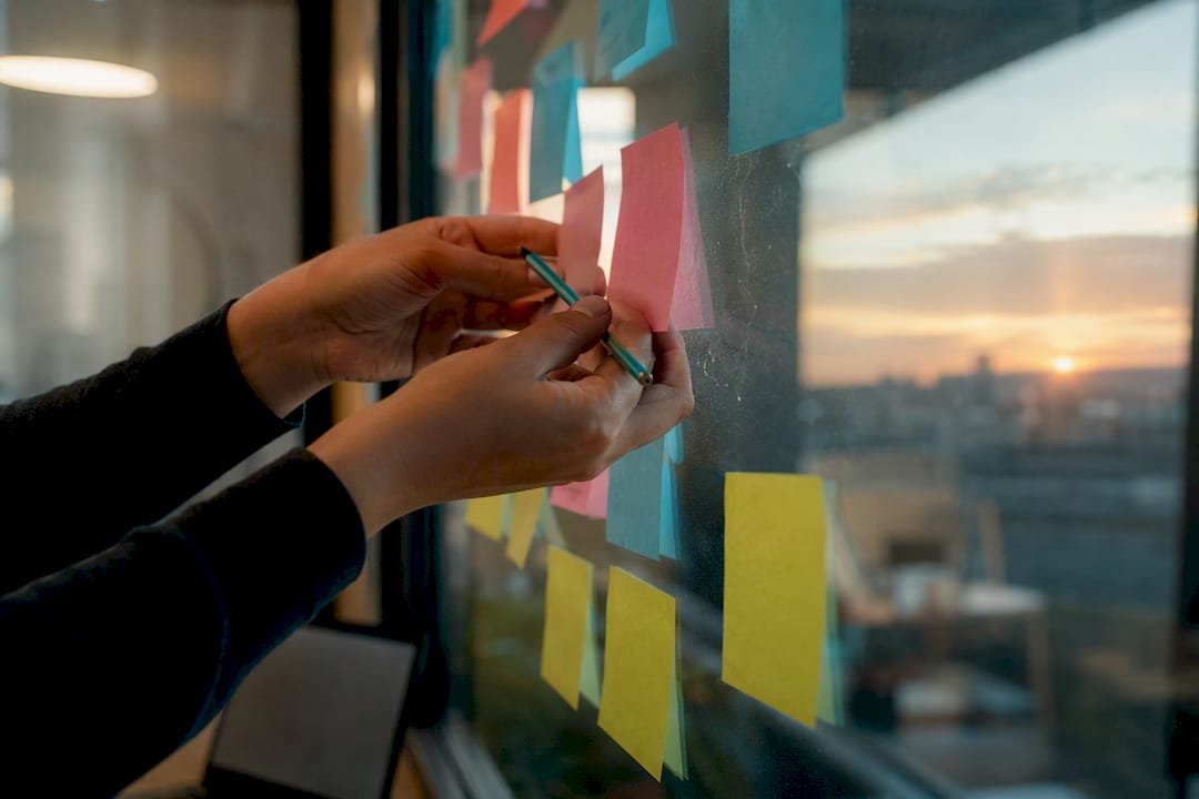 Hands arranging sprint backlog notes on board