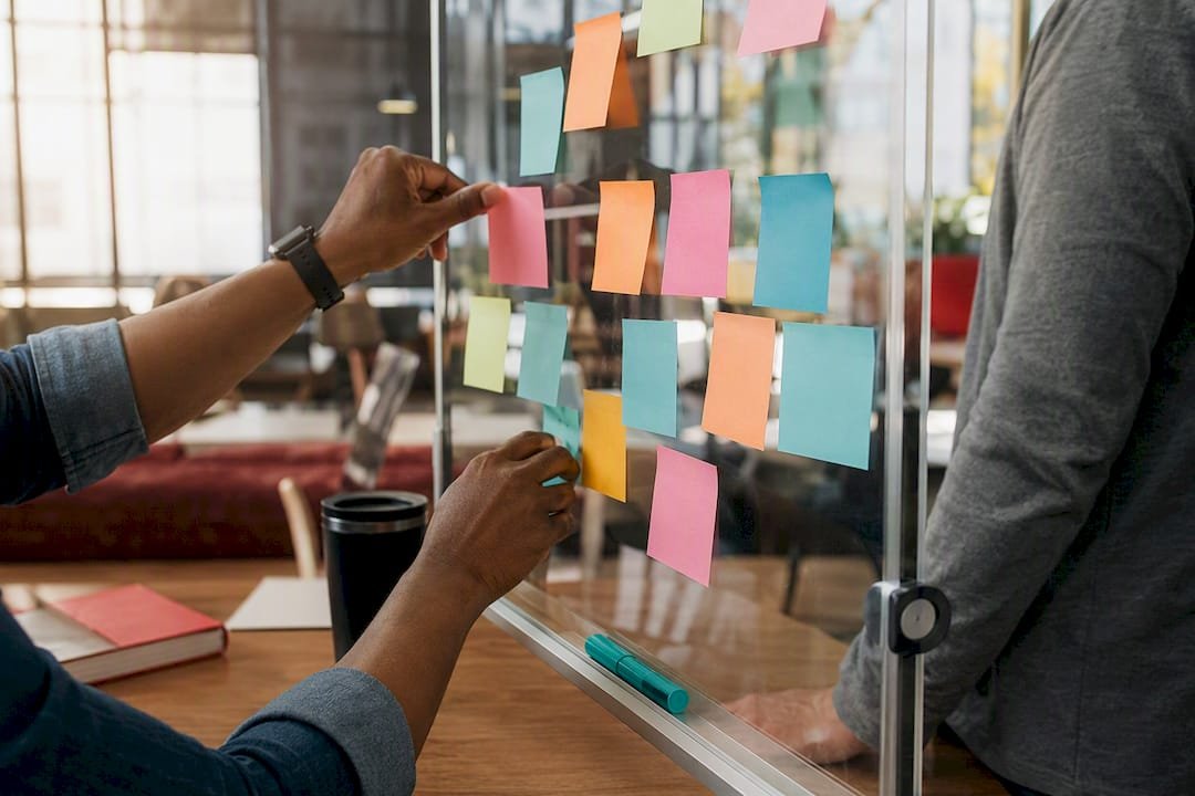 Hands applying sticky notes in Lean Six Sigma workshop